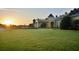 A grand exterior view of the estate with manicured lawn and sunrise at 4068 Stone Creek Loop, Lake Wales, FL 33859