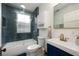 Stylish bathroom with blue tile in the shower and a vanity with gold fixtures and dark blue cabinets at 415 W Rich Ave, Deland, FL 32720