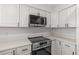 Close-up of a modern stainless steel oven and stovetop beneath an overhead microwave and white cabinets at 4940 Spring Run Ave, Orlando, FL 32819