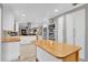 Modern white kitchen featuring a central butcher block island and stainless steel appliances at 7545 Lake Dr, Belle Isle, FL 32809