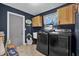 Laundry room with navy blue walls and wooden cabinets over a washer and dryer at 7545 Lake Dr, Belle Isle, FL 32809