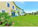 Lawn and backyard view of townhomes, colorful exteriors, and Adirondack chairs on patios at 8146 Coconut Pl, Kissimmee, FL 34747