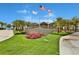 Lush resort entrance with colorful flowers, palm trees and three flags flying overhead at 8146 Coconut Pl, Kissimmee, FL 34747