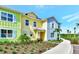 Colorful townhome with a front yard featuring tropical landscaping and a bench by the front door at 8146 Coconut Pl, Kissimmee, FL 34747