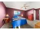 Bedroom with a ceiling fan, red accent wall and blue bedding at 8430 Pamlico St, Orlando, FL 32817