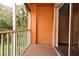 A balcony with orange walls looking out onto lush green foliage at 8775 Sartori St # 208, Orlando, FL 32829