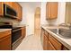 Galley kitchen with stainless steel appliances and light wood cabinets at 8775 Sartori St # 208, Orlando, FL 32829