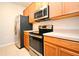 The kitchen features stainless steel appliances, wooden cabinets, and light countertops at 8775 Sartori St # 208, Orlando, FL 32829