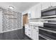 Kitchen featuring granite counters, white cabinets, black appliances and a decorative accent wall at 116 Cambridge Dr, Longwood, FL 32779