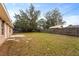 Spacious backyard with a wood fence, mature trees, and a concrete patio area at 1600 Amboy Dr, Deltona, FL 32738
