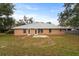 Brick home backyard with a patio, green grass, mature trees and fencing at 1600 Amboy Dr, Deltona, FL 32738