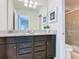 Bathroom featuring a granite countertop, dual sinks, framed mirrors, and a glass-enclosed shower at 1602 Lima Ave, Kissimmee, FL 34747