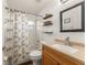 This bathroom offers a shower-tub combo, a single sink with wood cabinets, and open shelving above the toilet at 16224 Magnolia Hill St, Clermont, FL 34714