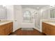 Bright bathroom with wood flooring, double vanity, a large soaking tub, and a glass shower at 16224 Magnolia Hill St, Clermont, FL 34714