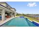 Spacious backyard featuring a large pool with a sun shelf, covered patio, and serene lake views at 16828 Sanctuary Dr, Winter Garden, FL 34787