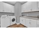 Functional laundry room with white cabinets, modern washer and dryer, and a utility sink at 16828 Sanctuary Dr, Winter Garden, FL 34787
