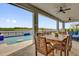 Covered patio featuring a wood dining set with a pool and lake view, perfect for outdoor entertaining and relaxation at 16828 Sanctuary Dr, Winter Garden, FL 34787