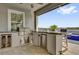 Outdoor kitchen with built-in grill, bar seating, and wine cooler, overlooking the pool and scenic lake views at 16828 Sanctuary Dr, Winter Garden, FL 34787