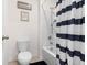 Cozy bathroom features a toilet, white tiled shower over tub, and striped curtain at 2024 Griffin Oaks Way, Tavares, FL 32778