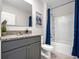 Well-lit bathroom featuring a grey vanity with granite countertop and a shower with blue curtain at 2219 Lake Preserve Cir, New Smyrna Beach, FL 32168