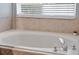 Bright bathroom features a large soaking tub with tile surround and window with blinds at 239 Bronze Leaf Ct, Apopka, FL 32703