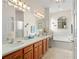 Bright bathroom featuring double sinks, tile floors, cherry wood cabinets, a shower and a soaking tub at 27019 Old English Ct, Leesburg, FL 34748