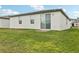 White single-story home featuring a lush backyard with a sliding glass door leading to a brick patio at 3069 Cassidy Ln, Haines City, FL 33844