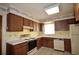 Traditional kitchen with wooden cabinetry, white appliances, tile flooring, and decorative wallpaper border at 380 Banyan Dr, Maitland, FL 32751