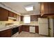 Traditional kitchen with wooden cabinetry, white appliances, tile flooring, and decorative wallpaper border at 380 Banyan Dr, Maitland, FL 32751
