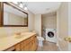 Bathroom featuring a wooden vanity, marble countertop, toilet, and laundry area at 4036 Shannon Brown Dr, Orlando, FL 32808