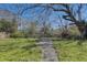 Overgrown backyard with mature trees, a weathered fence, and a concrete pathway leading into the space at 4155 Westgate Rd, Orlando, FL 32808