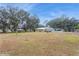 Expansive backyard featuring a well-maintained lawn, a swimming pool, and a detached home with mature trees at 5117 Cr 316A, Bushnell, FL 33513
