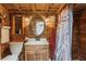 Rustic bathroom featuring a wood paneled wall, an oval mirror, a sink vanity, and a shower with a decorative curtain at 5117 Cr 316A, Bushnell, FL 33513