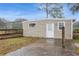 Modest home exterior featuring neutral siding, a white door, and a small window, accented by a simple landscaped yard at 5117 Cr 316A, Bushnell, FL 33513
