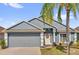 Charming single-story home with a gray two-car garage, complemented by a well-manicured lawn and lush palm tree at 551 Majesty Dr, Davenport, FL 33837