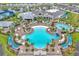 Aerial view of a resort-style community pool featuring sun loungers, palm trees, and a lively atmosphere with a bar and grill at 6105 Citrus Grove Ct, St Cloud, FL 34771