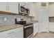 Close-up of the kitchen showcasing stainless steel appliances, granite countertops, and tiled backsplash at 10012 Lovegrass Ln, Orlando, FL 32832