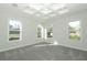 Bright bedroom featuring three windows, tray ceiling, and plush gray carpet at 1038 Dennis Ave, Orlando, FL 32807