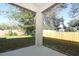 A covered patio overlooks a verdant lawn surrounded by trees and a wooden fence at 1038 Dennis Ave, Orlando, FL 32807