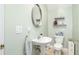 Bright bathroom featuring a pedestal sink, round mirror, and stylish decor at 11234 Willow Gardens Dr, Windermere, FL 34786