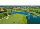 Aerial view of a meticulously maintained golf course with scenic water features and a grand clubhouse amid lush landscaping at 13319 Alderley Dr, Orlando, FL 32832