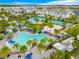 Aerial view of the community pool area with multiple pools, a volleyball court, cabanas, and plenty of palm trees at 13864 Sachs Ave, Orlando, FL 32827