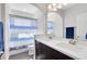 Bright bathroom featuring double sink vanity with white countertop and a shower with blue patterned curtain at 13875 Sachs Ave, Orlando, FL 32827