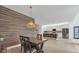 Dining room area with wood accent wall, stylish light fixture, wood-look floors, and modern kitchen at 14150 Aldford Dr, Winter Garden, FL 34787