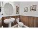 Charming powder room with oval mirror, pedestal sink, and wood-look accent wall at 14150 Aldford Dr, Winter Garden, FL 34787