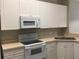 Bright kitchen with white cabinetry and appliances, including a microwave, stove, and refrigerator at 145 Reserve Cir # 113, Oviedo, FL 32765