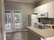 Well-lit kitchen boasts tile floors, white cabinets, and glass panel double doors to the outside at 145 Reserve Cir # 113, Oviedo, FL 32765