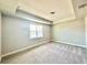 Neutral bedroom featuring plush carpeting, a tray ceiling, and a large window allowing for plenty of natural light at 1522 Bantam Way, Winter Park, FL 32792