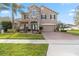 Two-story home showcasing a blend of stone and stucco, complemented by a brick driveway and manicured lawn at 1700 Leatherback Ln, St Cloud, FL 34771