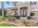 Elegant front entrance featuring stone accents, a covered porch, and decorative glass doors with lush landscaping at 1700 Leatherback Ln, St Cloud, FL 34771